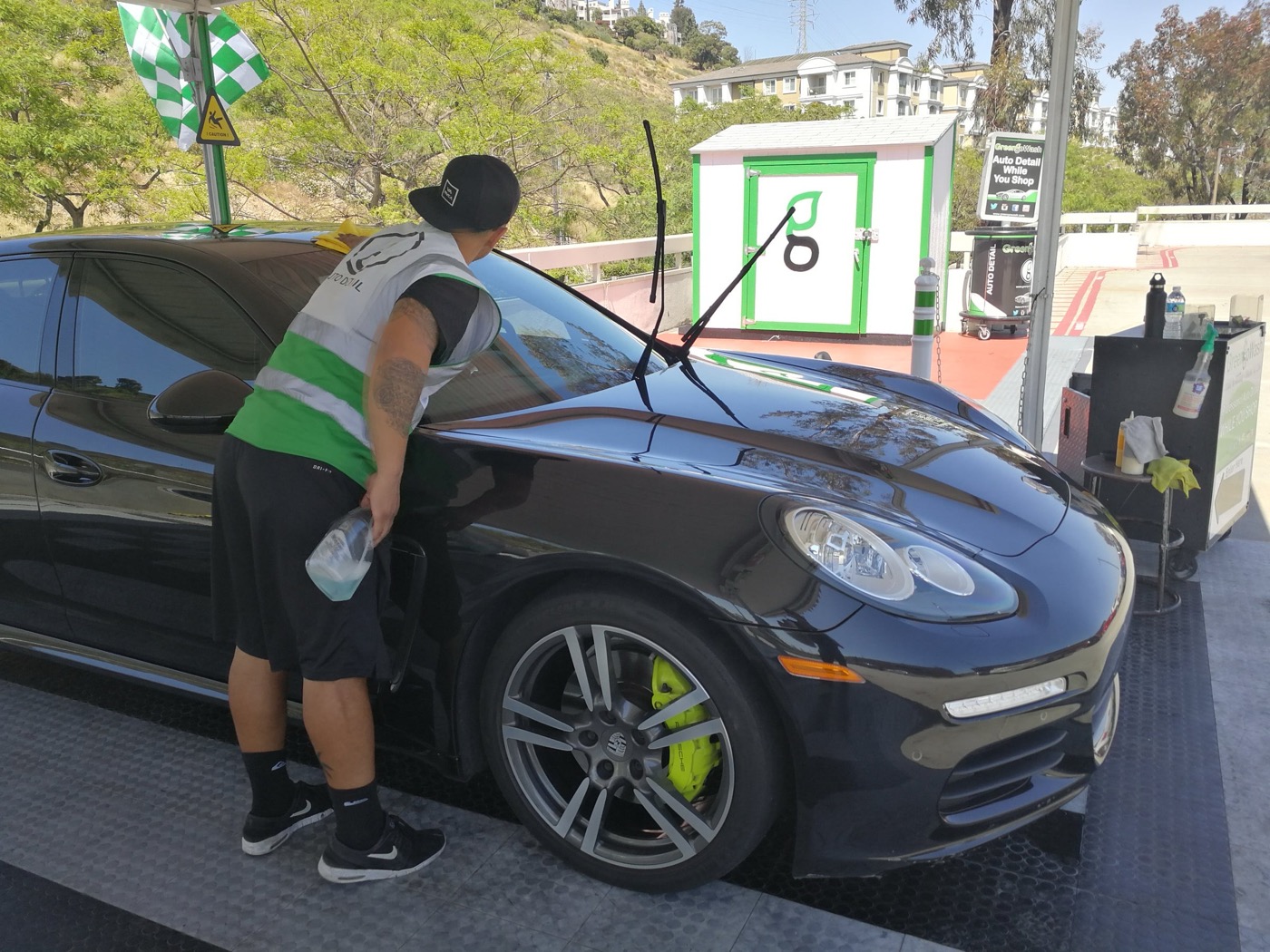Green Go Wash detailer hand-finishing a Porsche Panamera